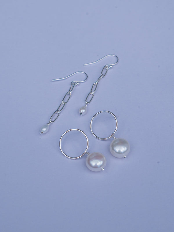 White freshwater pearls freely hang from sterling silver circle stud and chain earrings